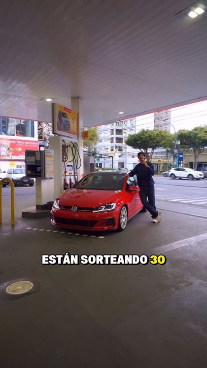 Un Golf GTI rojo cargando en una estación Shell
